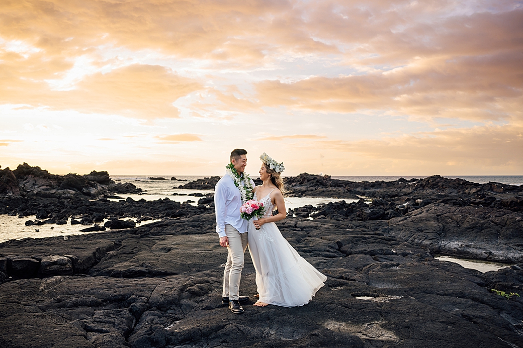 newlyweds in Hawaii on lava rocks at sunset