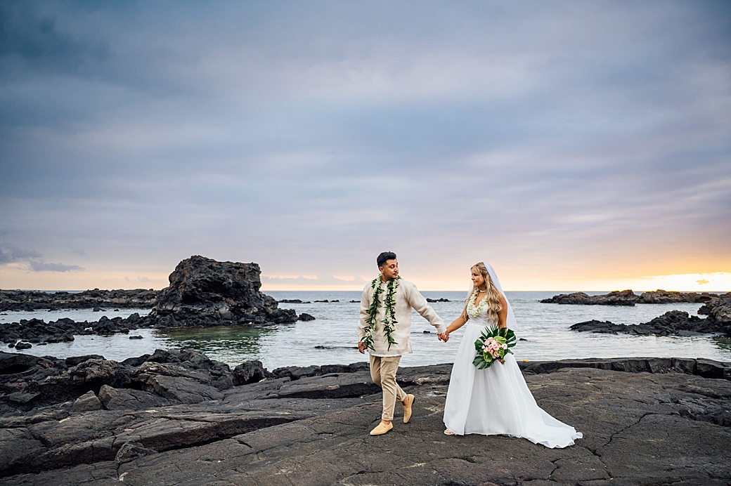 bride and groom walking over lava rock in kona