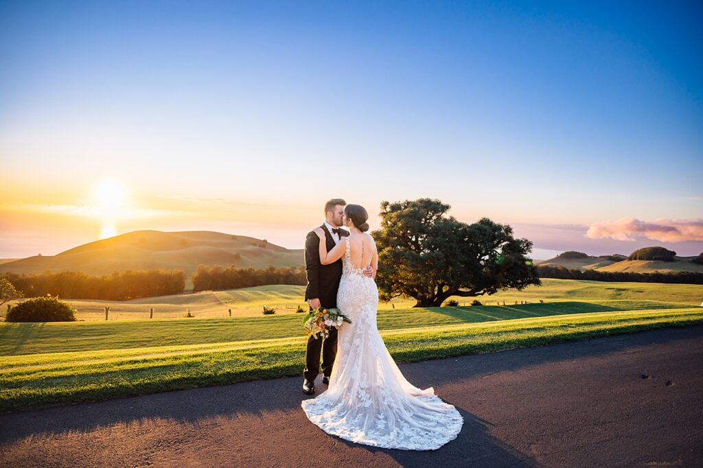 bride and groom kissing at sunset 