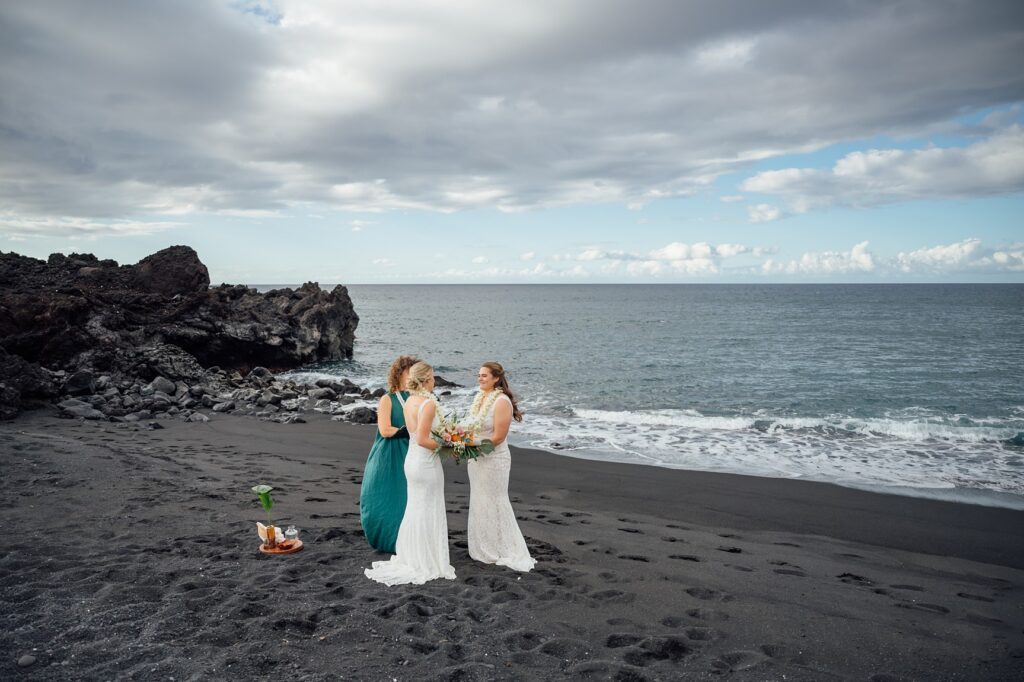 Officiant leading a blessing ceremony for a couple on a black sand beach on the Big Island